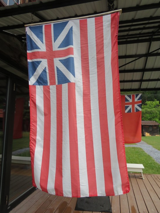 A Grand Union Flag hanging outside a cabin doorway and seen from the back.