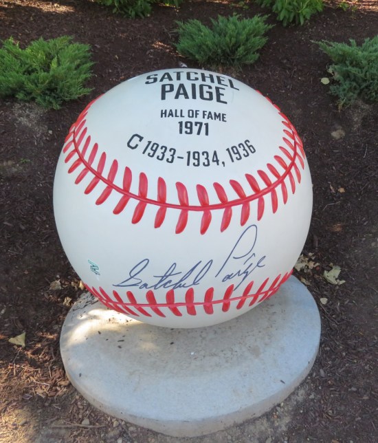 A giant replica autographed baseball mounted in the grounds outside a ballpark.
