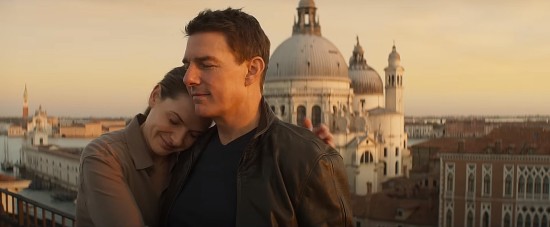 Tom Cruise and Rebecca Ferguson sharing a warm, quiet moment on a Rome rooftop with some basilica in the background.