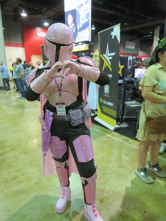 Sparkly pink Mandalorian, making a heart with her hands.