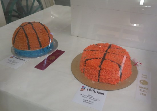 One standard-shaped cake iced to look like a basketball, and one cake made to look like a basketball cut in half.