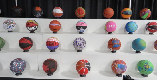 White bleachers holding dozens of kid-painted basketballs.