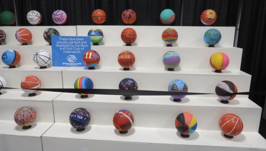 White bleachers holding dozens of kid-painted basketballs.