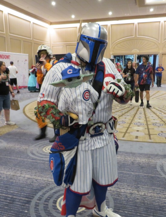 Chicago Cubs-themed Mandalorian armor, holding a Grogu doll dressed in cute tiny Cubs baseball togs.