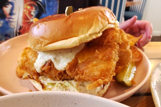 Closeup of a fish sandwich over half the size of Anne's head.