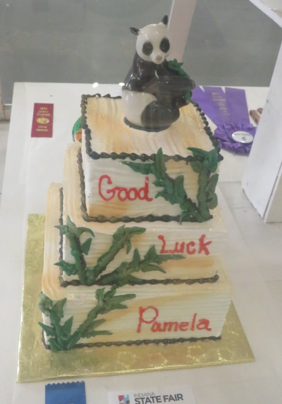 A three-level cake with a panda on top and the iced message "Good Luck Pamela".