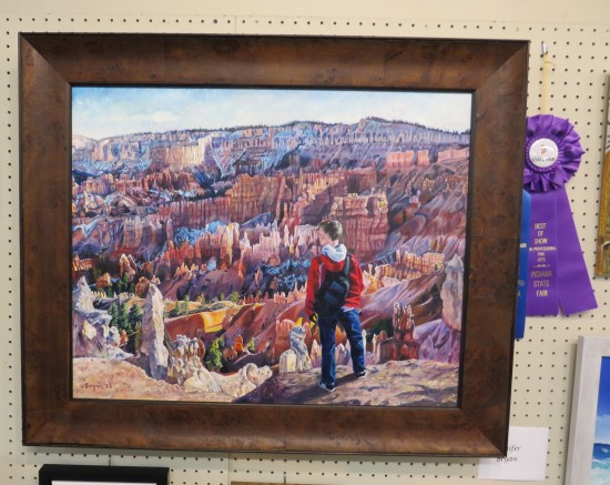 Painting: dude standing at the edge of the Grand Canyon. Lots of rock formations, some cacti.