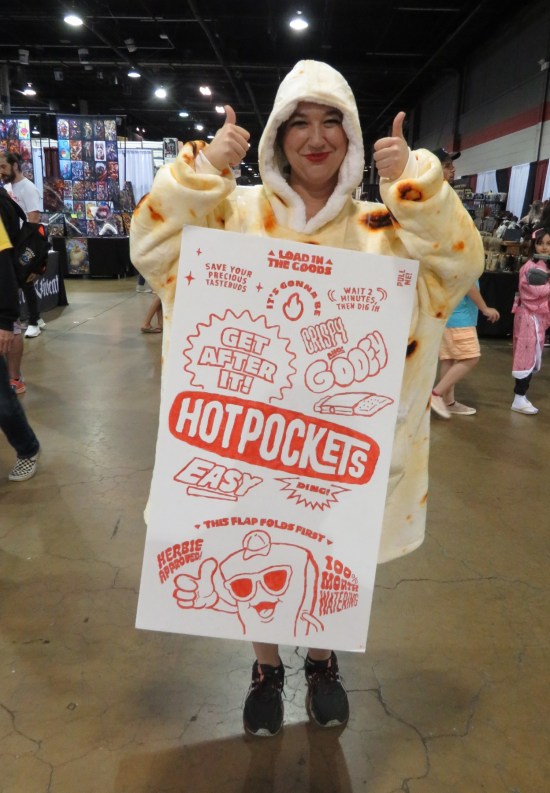 A woman wearing a giant-sized Hot Pocket cardboard sleeve.
