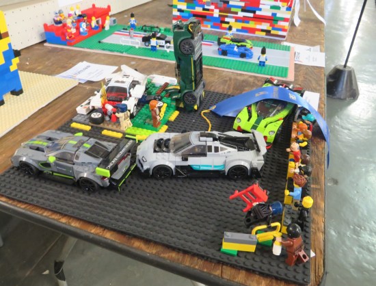 Three rego sports cars in a line. A fourth one is half-disassembled for repairs.