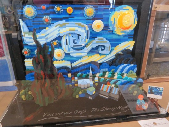 Van Gogh's Starry Night rendered in Lego, with a tiny Lego van Gogh in the corner of the display.
