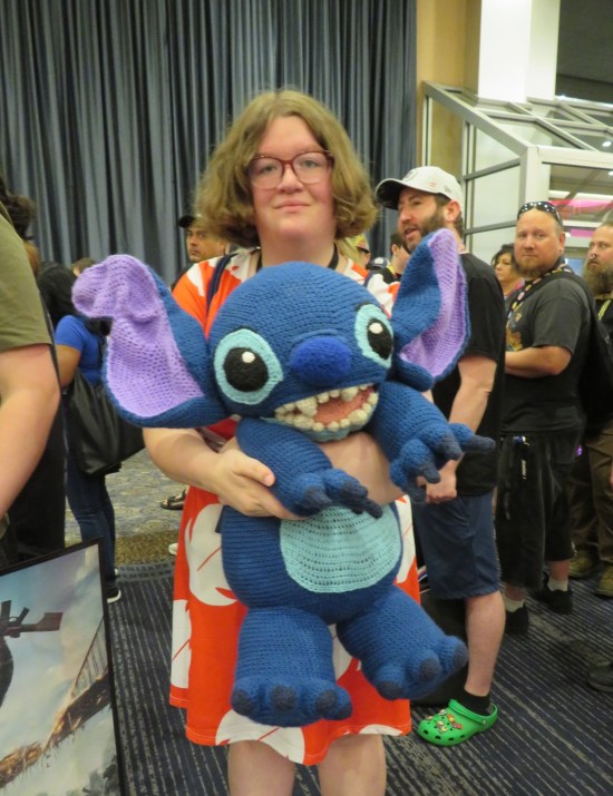 Lilo cosplayer holding a large Stitch doll.