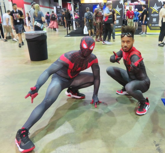 Miles Morales cosplayers in two of his different suits.