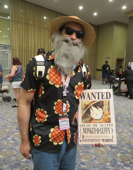 Monkey D. Luffy wearing a straw hat, sunglasses, and fake beard while carrying a Wanted poster for himself.