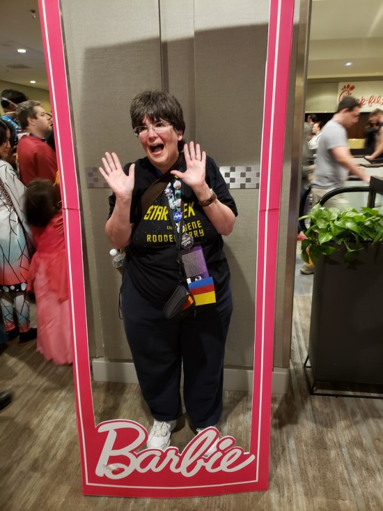 my wife doing jazz hands inside a human-sized Barbie box that someone just left in a hallway.
