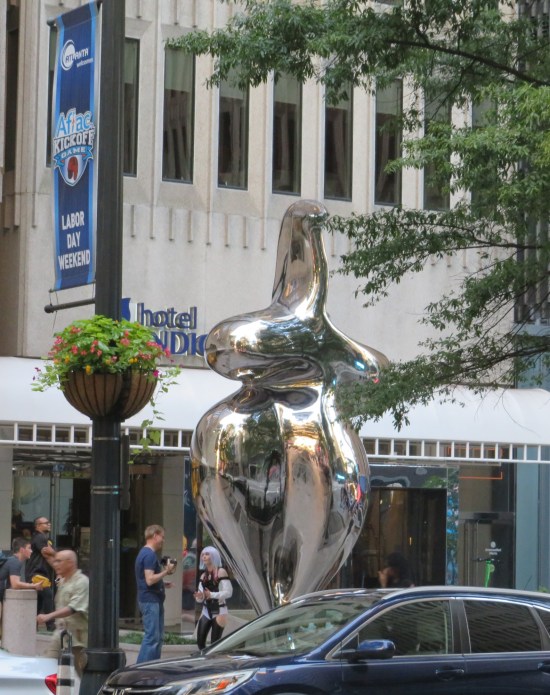 Stainless steel sculpture that's all curves and looks like a fat, sitting bird with pointy arms instead of wings.