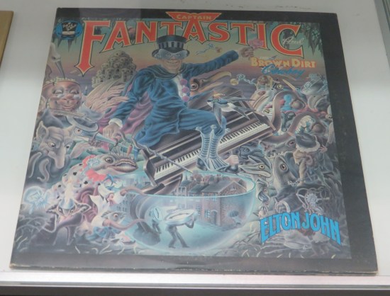 1975 Elton John album Captain Fantastic and the Brown Dirt Cowboy LP, with a very Pop Art cover of the singer dressed in all blue, including top hat and masquerade mask.