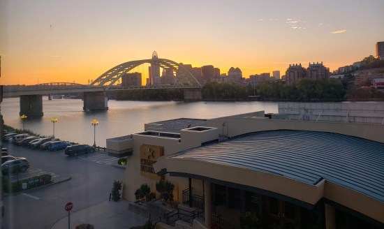 Downtown Cincinnati at sunset as viewed from across the Ohio River, with a bridge in the way.