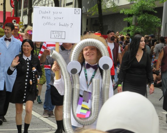 Clippy cosplay, flanked by Wednesday and Morticia Addams.