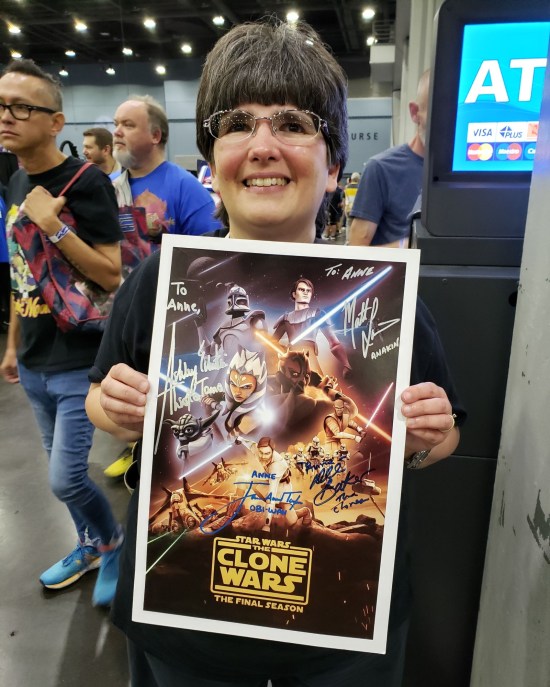 Anne proudly holding a Clone Wars poster with four autographs on it.