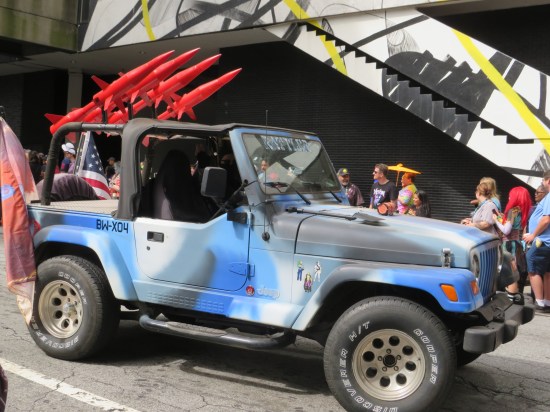 A blue-camouflaged jeep with four big plastic red missiles ready for launching off the back.