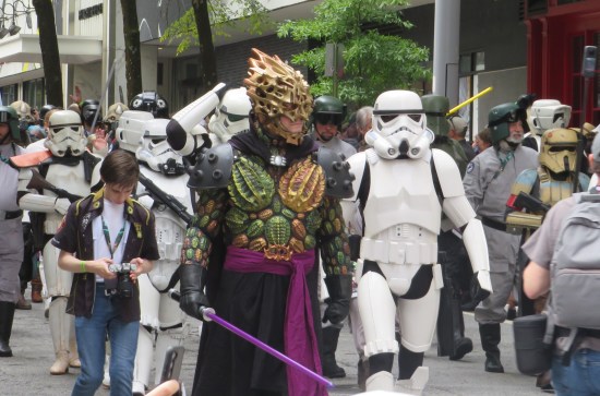 Darth Bane covered in large plastic seashells, carrying a purple lightsaber. Stormtroopers also abound.