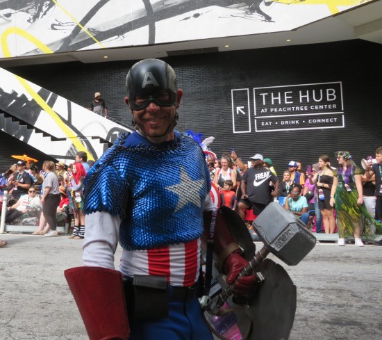 Battle-damaged Captain America carrying his broken shield and Thor's hammer Mjolnir.