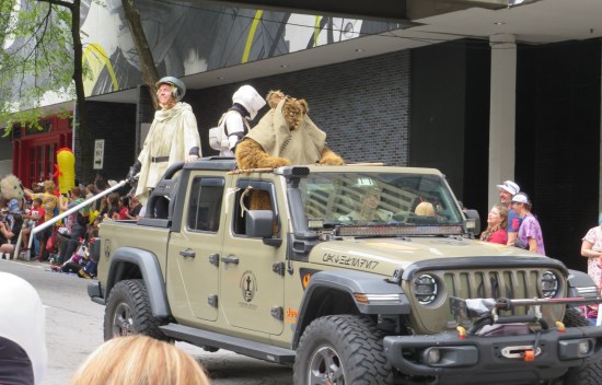 Jeep with "Return of the Jedi" soldier cosplayers plus one Ewok standing in the passenger seat.