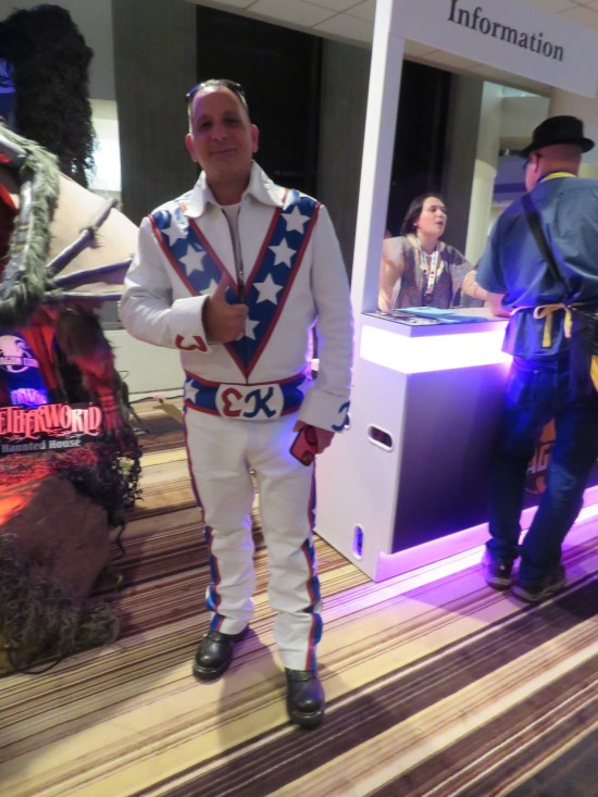 cosplay: 1970s stuntman Evil Knievel, standing next to a neon information booth.