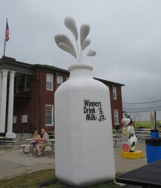 A giant milk bottle outside with big fake milk drops floating above it as if spraying out.