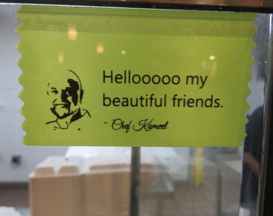 Giant green ribbon in the restaurant window: "Hellooooo my beautiful friends. - Chef Kameel". On the left side is a drawing of Kameel.