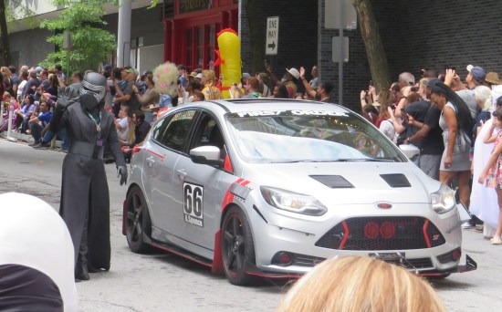 Kylo Ren cosplayer walking next to a small gray with a "First Order" decal on the front window and the number 66 on the side.