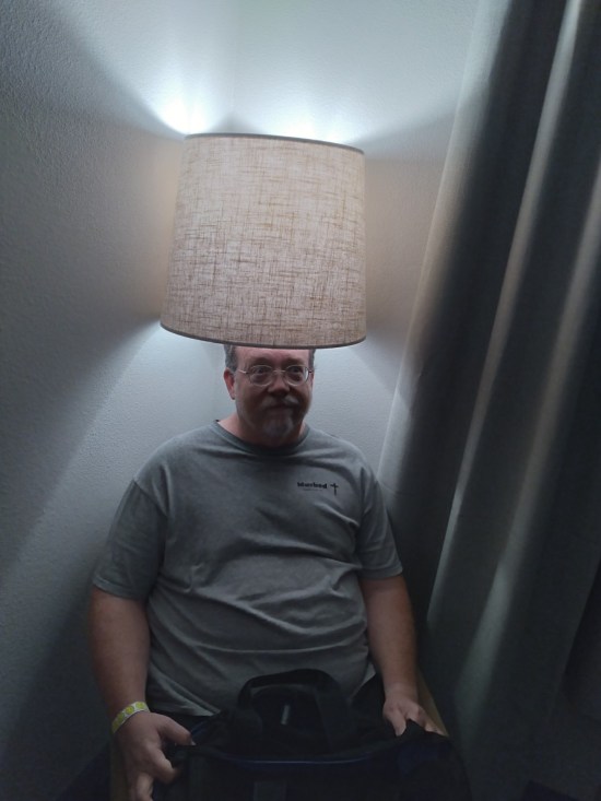 Me sitting in a chair in the corner, which also has a lamp above it, and my head is inside the lampshade because this was a stupid furniture arrangement.