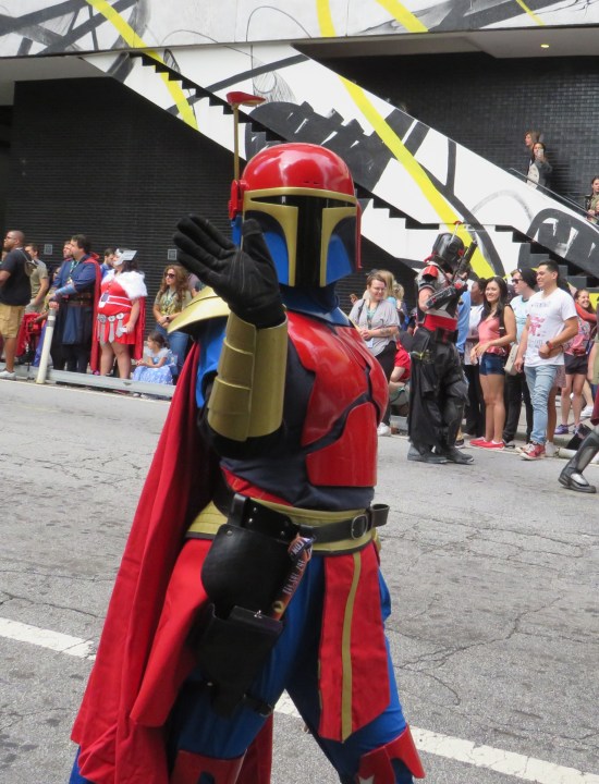 Bright red and blue Madalorian armor with bronze highlights. Waving at the camera.