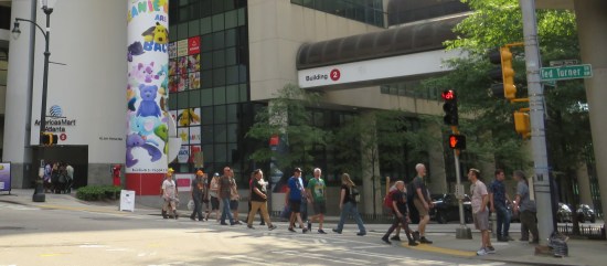 White building with Pokemon decor outside and uncostumed fans walking up and down the block.
