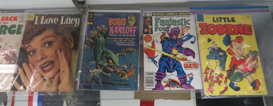 Four comics in a vitrine, three of them old.