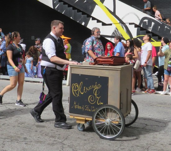 Guy walking a sales cart with "Olivander Jr." on the side, spelled differently from the books.