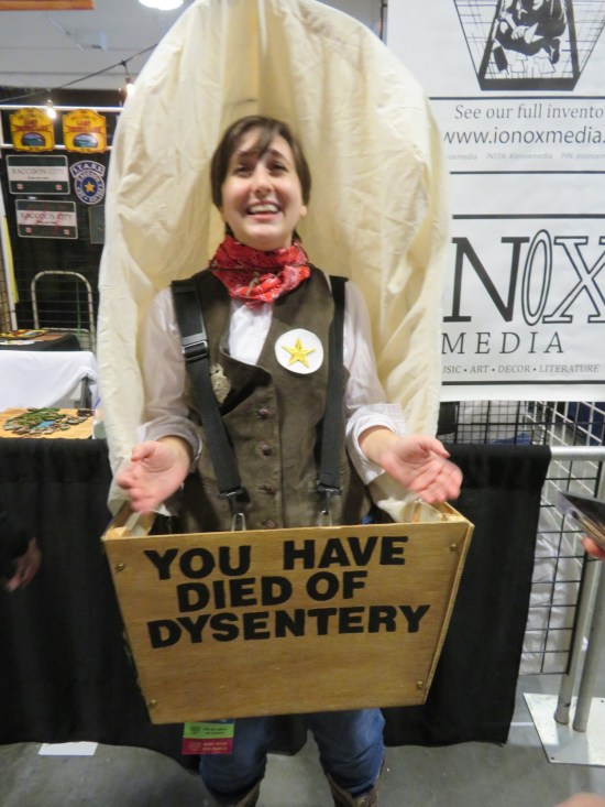Cosplay: woman wearing a wagon. On the front, the wagon reads, "You have died of dysentery."