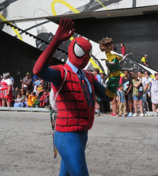Kid wearing a Spider-Man mask and glove; red vest with thick, widely spaces crosshatch lines; and a Doctor Octopus puppet on his other hand.