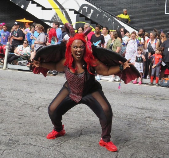 lady in a demon costume with big red horns, red-and-black leaterhy wings, and red contact lenses.