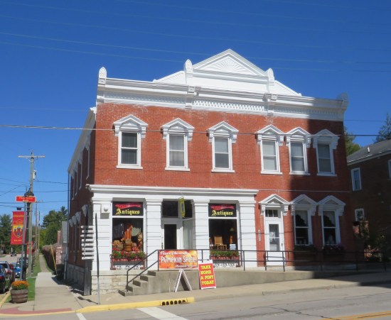 Two-story brick building with white roof and trimmings, plus sideways concrete steps leading up to the front door.