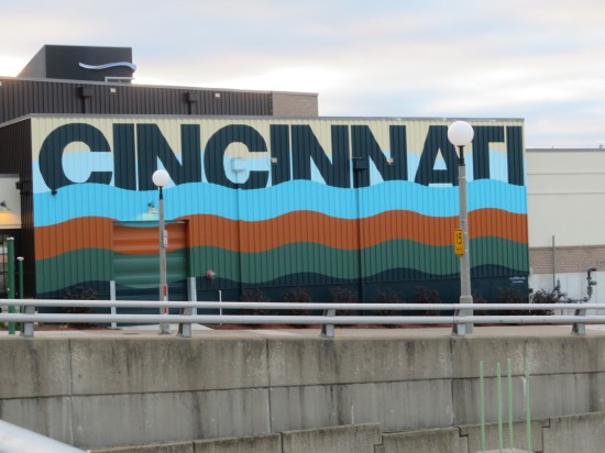Building with Cincinnati's name painted large and underlined with waves of baby blue, brown, greenish-grey and indigo.