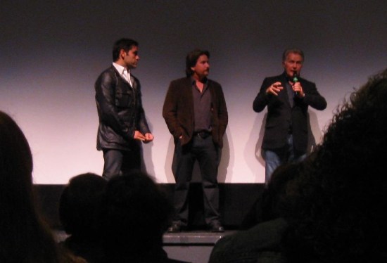 David Alexanian, Emilio Estevez, and Martin Sheen (holding the microphone) standing at the front of a poorly lit theater whose screen is blank.