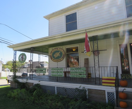 Gift shop on the first floor of a two-story ordinary house. The sign calls it Die Goldene Schildkröte Handelszentrum. Fence decor includes a German flag and list of products inside.