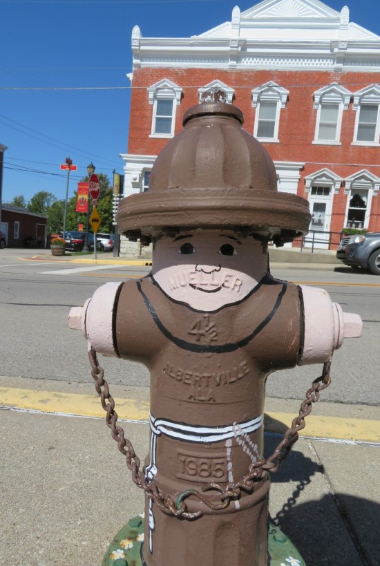 Fire hydrant painted like a hooded monk in brown robes.