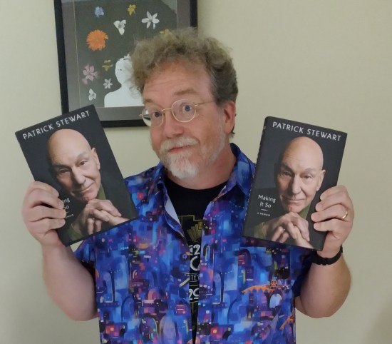 Me holding a copy of Patrick Stewart's memoir "Making It So" in each hand. The front cover is a closeup of Stewart's smiling head against a black background, hands stacked under his chin.