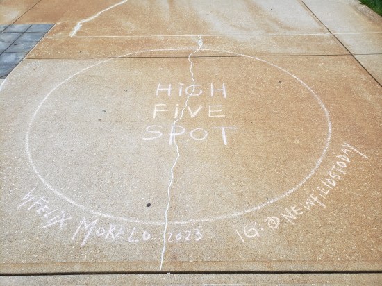 Large sidewalk chalk circle labeled "High Five Spot", signed by artist Felix Morelo.