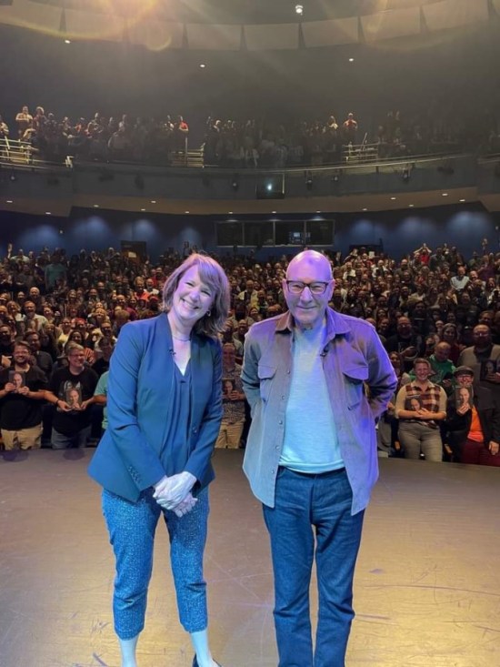 A smiling Patrick Stewart alongside an NPR host on stage, with our audience behind them.