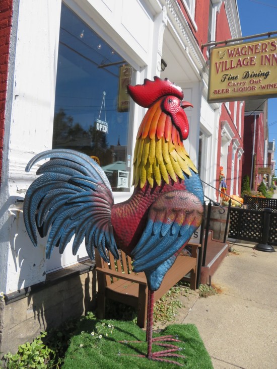 A colorful rooster sculpture standing in front of a restaurant called Wagner's Village Inn.