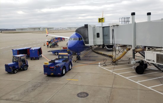A blue Southwest Airlines plan hooked up to a collapsible tunnel leading into the terminal.