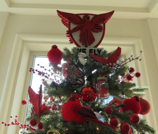 Christmas tree swarming with stuffed cardinals. The topper is a red angel emblem that says "WE FLY".
